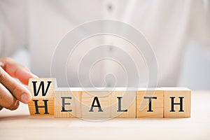 Hand flip wooden cube with word wealth to health