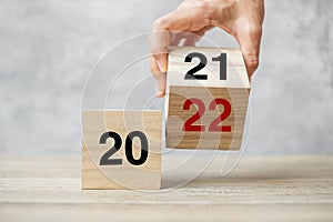 Hand flipping block 2021 to 2022 text on table. Resolution, strategy, plan, goal, motivation, reboot, business and New Year