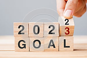 Hand flipping block 2022 to 2023 GOAL text on table. Resolution, strategy, plan, motivation, reboot, business and New Year holiday