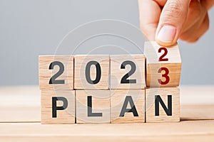 Hand flipping block 2022 to 2023 PLAN text on table. Resolution, strategy, goal, motivation, reboot, business and New Year holiday