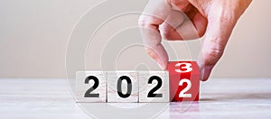 Hand flipping block 2022 to 2023 text on table. Resolution, strategy, plan, goal, motivation, reboot, business and New Year