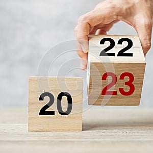 Hand flipping block 2022 to 2023 text on table. Resolution, strategy, plan, goal, motivation, reboot, business and New Year