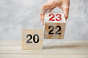 Hand flipping block 2022 to 2023 text on table. Resolution, strategy, plan, goal, motivation, reboot, business and New Year