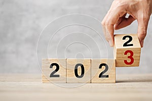 Hand flipping block 2022 to 2023 text on table. Resolution, strategy, plan, goal, motivation, reboot, business and New Year