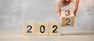 Hand flipping block 2022 to 2023 text on table. Resolution, strategy, plan, goal, motivation, reboot, business and New Year