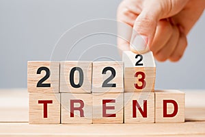 Hand flipping block 2022 to 2023 TREND text on table. Resolution, idea, goal, motivation, reboot, business and New Year holiday