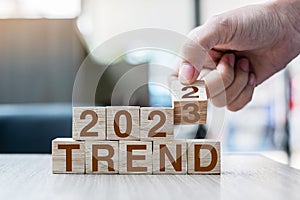 Hand flipping block 2022 to 2023 TREND text on table. Resolution, idea, goal, motivation, reboot, business and New Year holiday