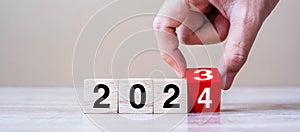 hand flipping block 2023 to 2024 text on table. Resolution, strategy, plan, goal, motivation, reboot, business and New Year