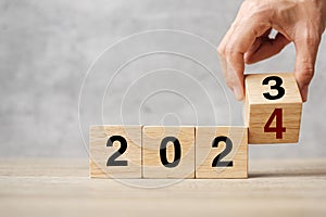 hand flipping block 2023 to 2024 text on table. Resolution, strategy, plan, goal, motivation, reboot, business and New Year