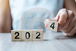 hand flipping block 2023 to 2024 text on table. Resolution, strategy, plan, goal, motivation, reboot, business and New Year