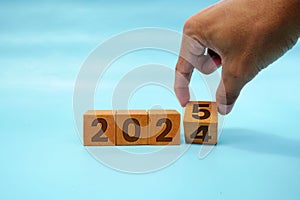 Hand flipping block 2024 to 2025 text on table