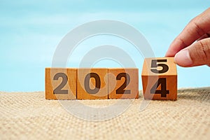 Hand flipping block 2024 to 2025 text on table