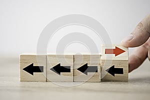 Hand flipping wooden cube block arrow from change left to right for business disruption and different thinking idea photo