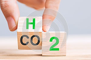 Hand flipping wooden cube blocks with CO2 Carbon dioxide, change to H2 Hydrogen text on table background. Free Carbon,