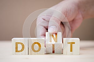 Hand flipping wooden cubes for change wording between don`t to do it.Mindset for career growth business