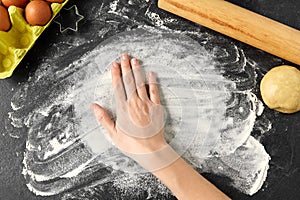 Hand with flour, dough and rolling pin on table