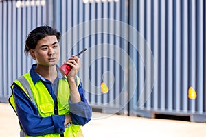 Hand Foreman holding walkie- talkie for control working at Container cargo site. Handheld walkie talkie for outdoor