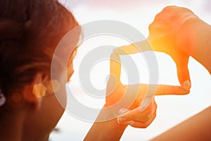 Hand framing view distant over sunset