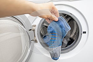 Hand in front of front loading washing machine found a blue missing sock