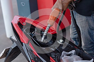 Hand fuel nozzle in pouring to motorcycle at gas station