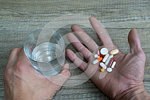 hand full of colored medicines and a glass of water for self consumption