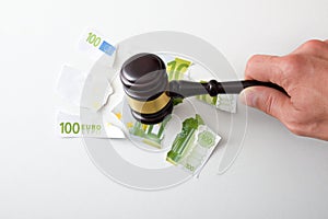 Hand with gavel breaking bank note financial judgment concept photo