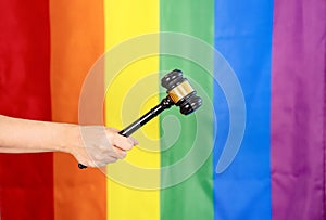 hand of gay pride holding wood gavel or judge hammer background lgbtq rainbow flag