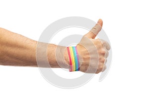 Hand with gay pride rainbow wristband shows thumb