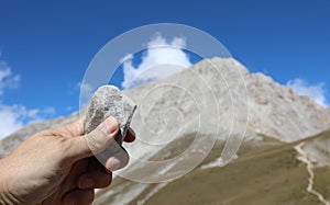 hand of the geologist holding a stone and the mountain called Gr