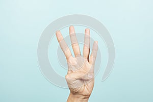 Hand gesture. Female hand shows number four. Woman hand pointing up with three fingers on light blue background