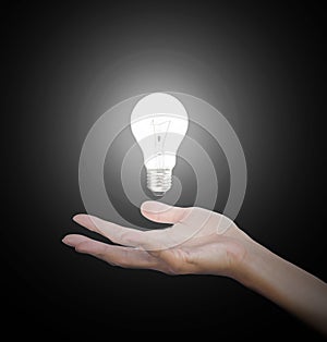 Hand gesture holding floating light bulb with light on dark background. Conceptual thinking new idea. Concept idea.