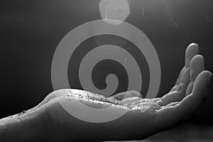 Hand gesture receiving the light of blessings in spiritual concept on black and white abstract art background. New hope concept.