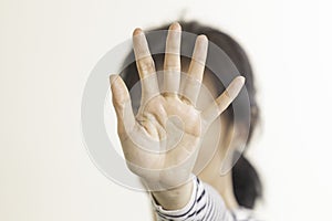 Hand gesture Stop, No. Woman rises her hand up, covering her face and showes stop gesture by hand trying to stop any