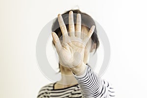 Hand gesture Stop, No. Woman rises her hand up, covering her face and showes stop gesture by hand trying to stop any