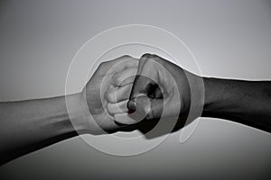 Hand gestures - Fist bump of two differenend - multi coloured hands in black and white