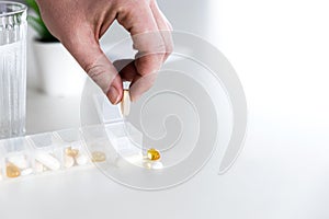 Hand get tablet from medical pill box for daily take medicine at the table