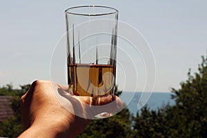 In the hand of the girl Apple juice in the glass. on the background of the sky.