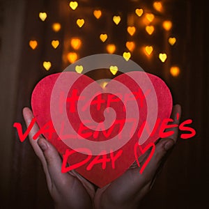 Hand of a girl holding paper red heart, heart bokeh