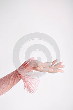 Hand of a girl in a pink lace dress with frills on a white background raised up