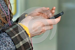 Hand of a girl who chooses music on her smartphone