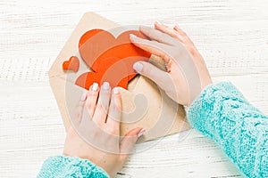 Hand of girl writing love letter on Saint Valentines Day. Handmade postcard with red heart shaped figure. 14 February holiday