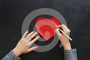 Hand of girl writing love letter on Valentine Day.