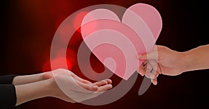 Hand giving heart shape to woman against red bokeh