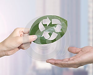 Hand giving leaf with hole of recycling symbol, resource recovery