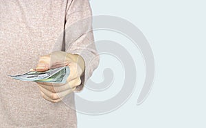 Hand giving money US dollars on grey background, concept of investment, success and profitable