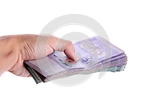 A hand giving a stack of Malaysian Ringgit