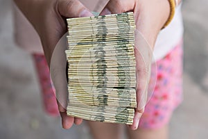 Hand giving Thai banknotes