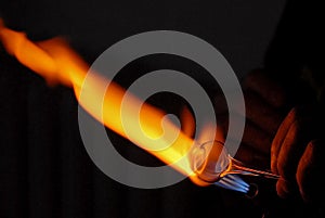 Hand of a glass blower heating a