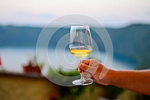 Hand with glass of cold dry white wine served outdoor in cafe at night in Italy