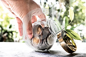 Hand and Glass jar piggy bank with coins. Plan your savings, run a growing business for success and save for retirement